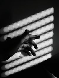 High angle view of sunlight falling on hand by wall