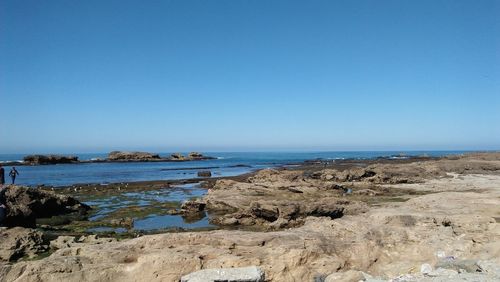 Scenic view of beach against clear blue sky