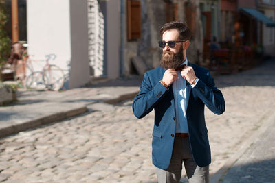 Portrait of young man standing on footpath