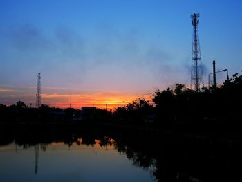 Silhouette trees and electricity pylon against sky during sunset