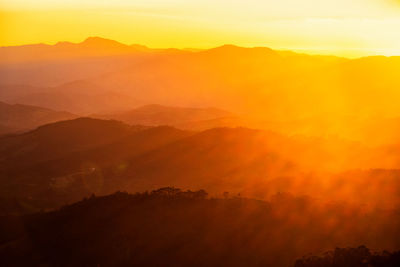 Scenic view of silhouette mountains against orange sky