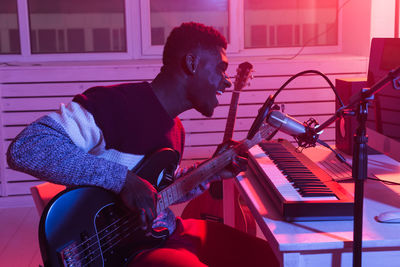 Side view of young man playing guitar