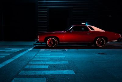 Red vintage car on road at night