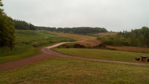 Scenic view of road amidst field against sky