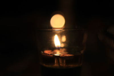 Close-up of illuminated candle over black background