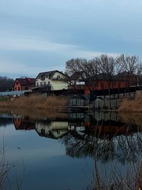 Houses by lake against sky