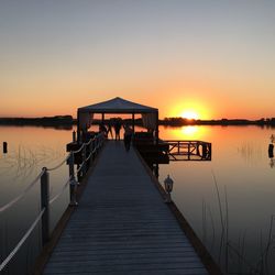 Pier over lake against sky during sunset