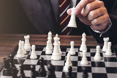 Midsection of businessman playing chess at table