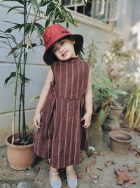 Portrait of girl standing against potted plants