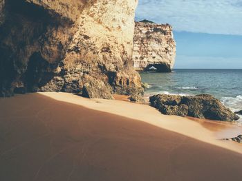 Rock formations at beach on sunny day