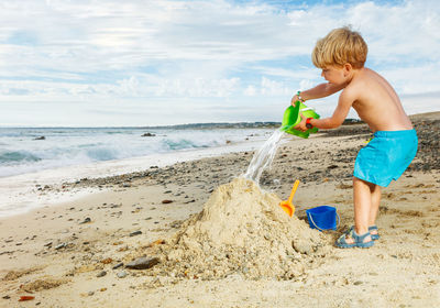 Side view of boy playing with straw at beach