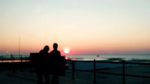 Silhouette of people in sea at sunset