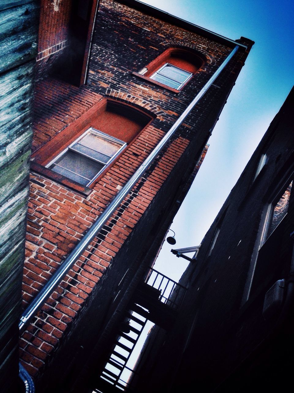 architecture, built structure, building exterior, low angle view, window, building, sky, balcony, residential building, city, residential structure, clear sky, day, sunlight, no people, railing, blue, outdoors, glass - material, architectural feature