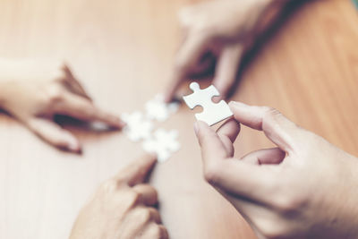 Close-up of hands playing jigsaw puzzle on table