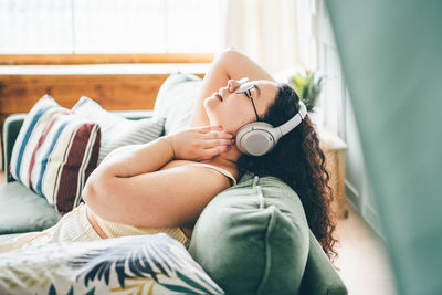 Midsection of woman using mobile phone while lying on bed at home