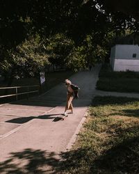 Rear view of woman walking on footpath by trees