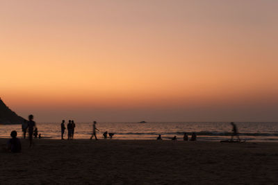 Silhouette people on beach against sky during sunset