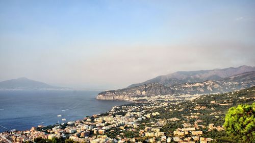 Aerial view of town by sea against sky