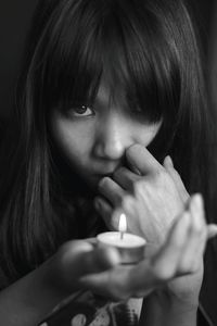Portrait of young woman holding illuminated tea light