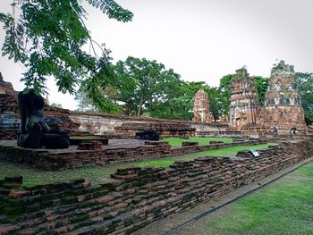 Old temple by building against sky