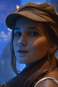 Close-up portrait of smiling girl by window at night