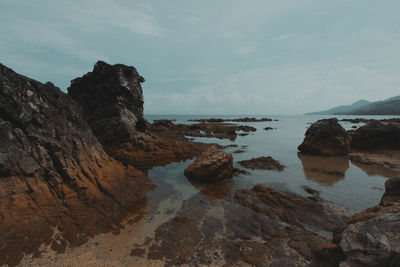 Rock formations on shore against sky