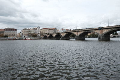 Arch bridge over river against sky in city