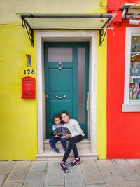 Full length of woman standing against yellow door