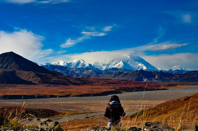 Rear view of woman standing on mountain against sky