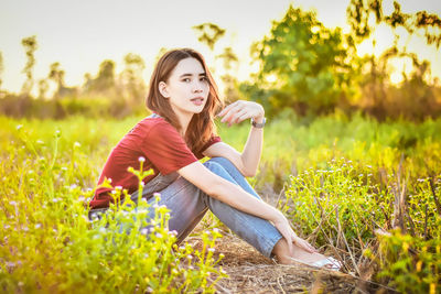 Portrait of young woman sitting on field