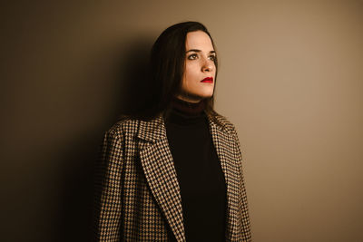 Portrait of beautiful young woman standing against wall