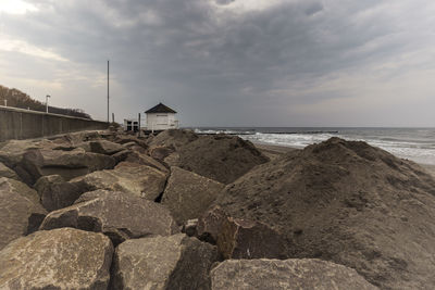 Rocks on beach by sea against sky