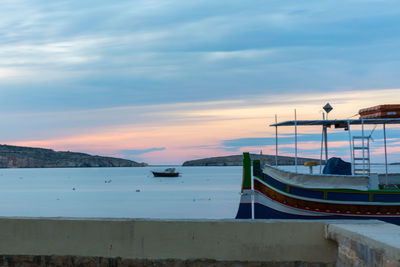 Boats moored in sea against sky during sunset