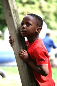 Boy looking away on wooden post