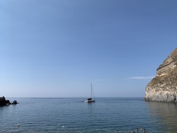 Sailboat in sea against clear blue sky