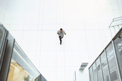 High angle view of businessman using mobile phone while walking in modern office