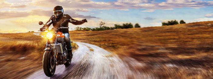 Man riding motorcycle on road against sky