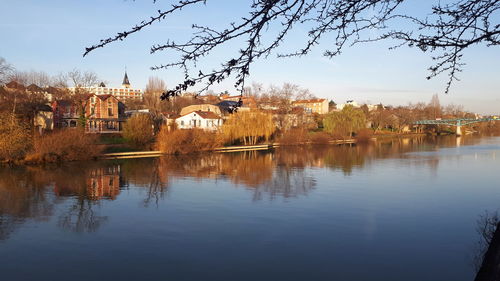 Buildings by river against sky