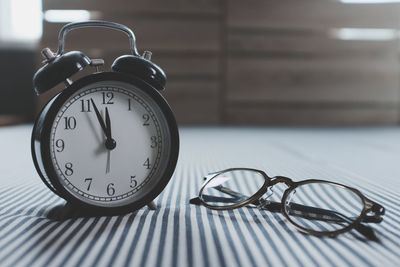 Close-up of alarm clock and eyeglasses on striped tablecloth