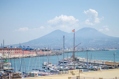 Sailboats moored at harbor against sky