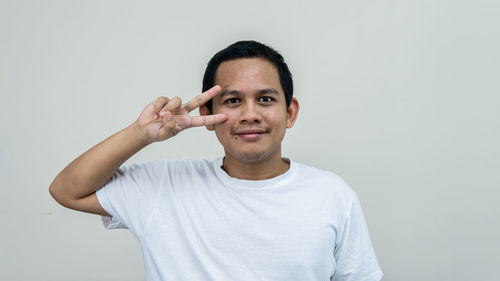 Portrait of young man standing against white background