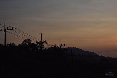 Silhouette electricity pylon against sky during sunset