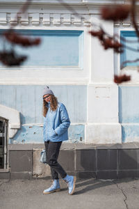 Side view of young woman standing against building