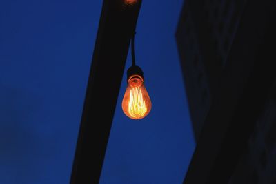 Illuminated light bulb against sky at night