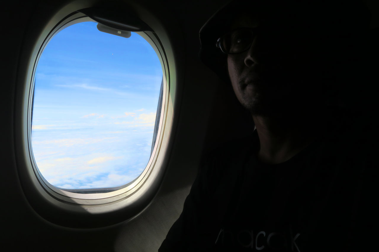 LOW ANGLE VIEW OF WOMAN SITTING IN AIRPLANE