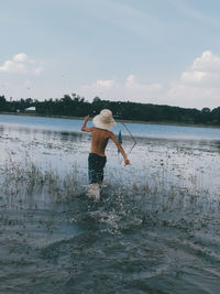 Rear view of boy in sea against sky