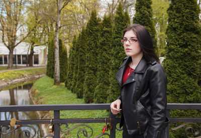 Woman standing by railing against trees