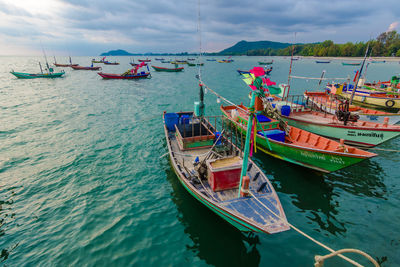 Fishing boats moored at harbor against sky