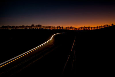 Light trails on road against sky at night