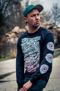 Young man looking away while standing outdoors